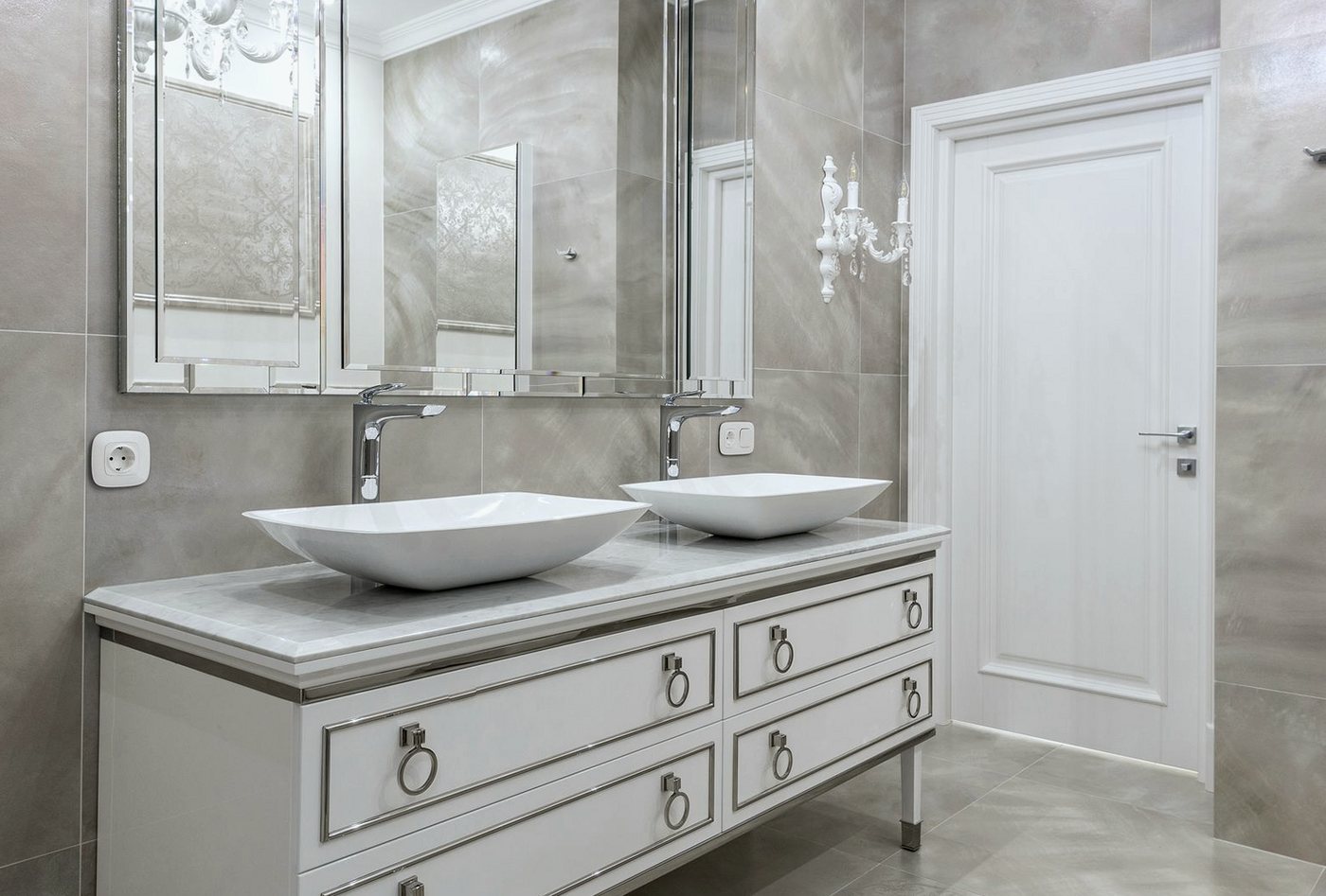 Large-format grey wall tiles around a pair of basins