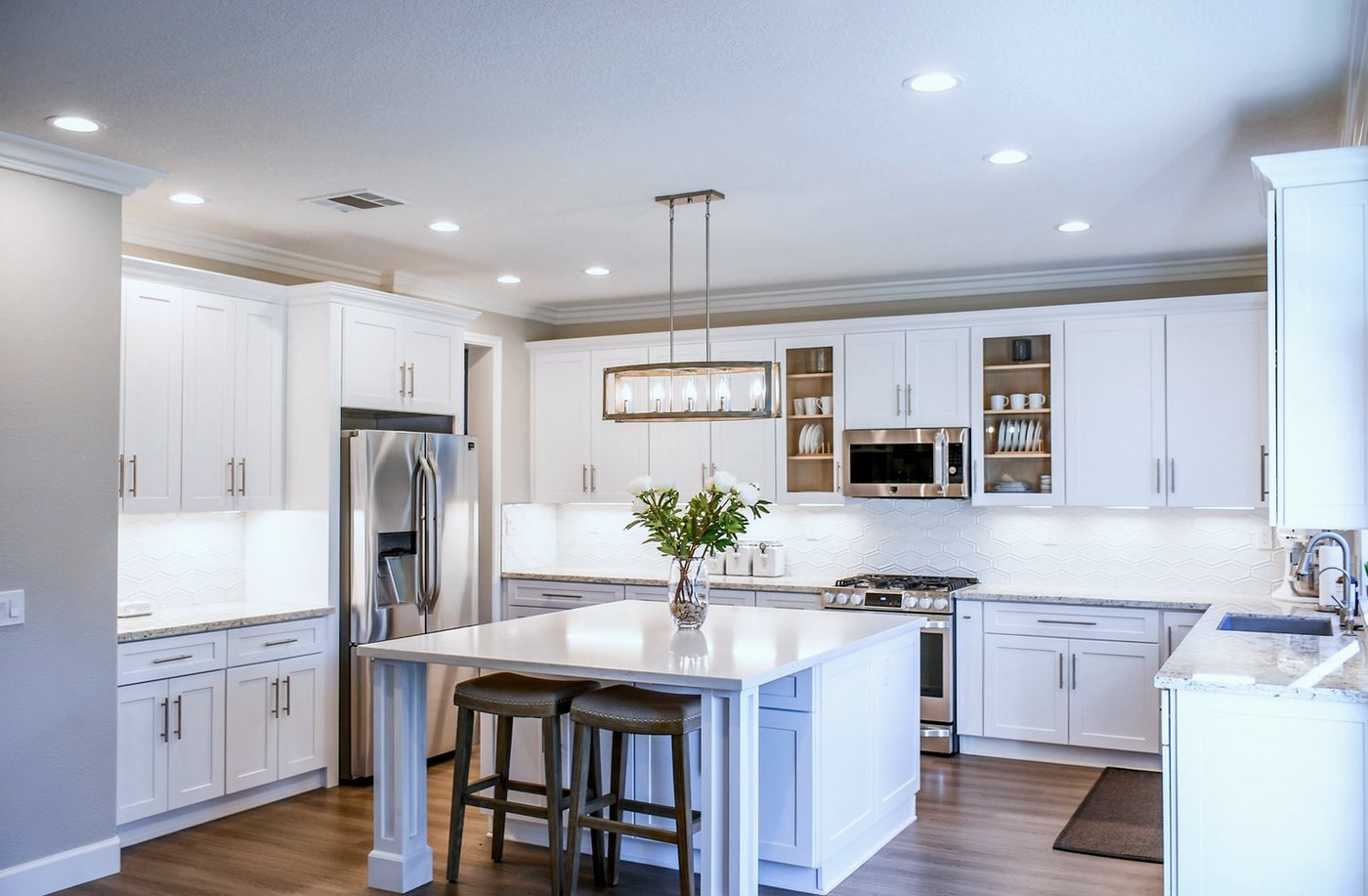 Newly fitted white kitchen with an island, hexagonal splashback tiles and granite worktops